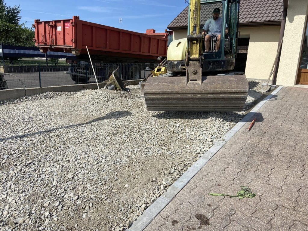 t-p-j.fr - engin de chantier étalant des graviers dans une cour de maison