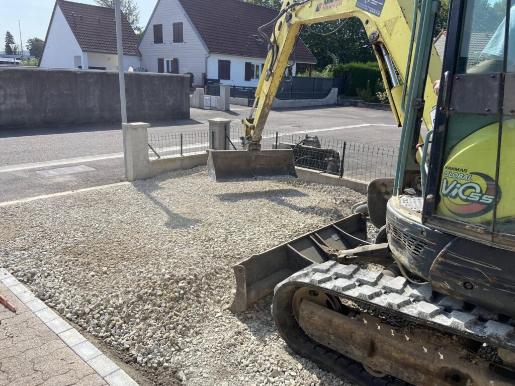 t-p-j.fr - engin de chantier étalant des graviers dans une cour de maison