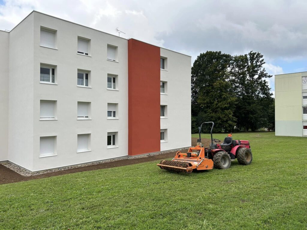 t-p-j.fr - engin de chantier dans la pelouse devant un immeuble avant de retourner la terre