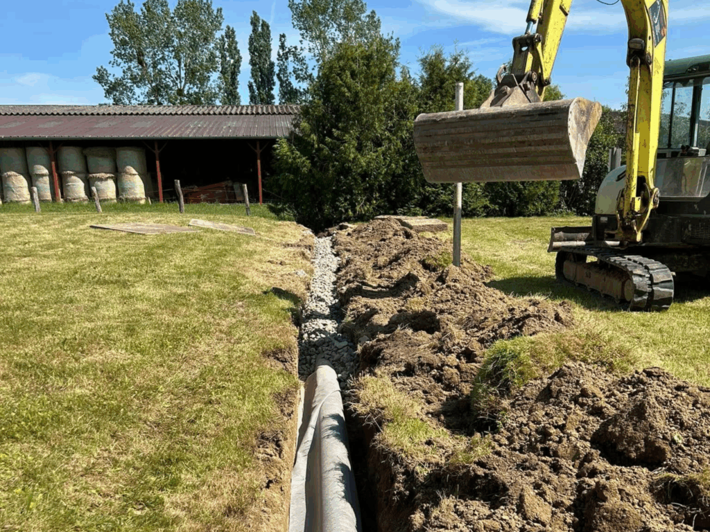 t-p-j.fr - engin qui recouvre un tuyau dans une tranchée avec des graviers